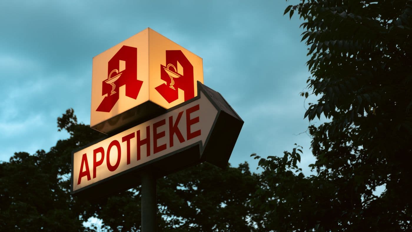 Rotes Apotheken-A über einem Apothekenschild in der Dämmerung